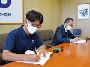 合弁契約書に署名するROSの藤本和之代表(手前)と徳島新聞社の池上社長=徳島市の新聞放送会館