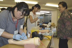 県ナースセンター職員の指導で、採血を練習する復職研修参加者（左側）＝徳島市北田宮１の県看護会館