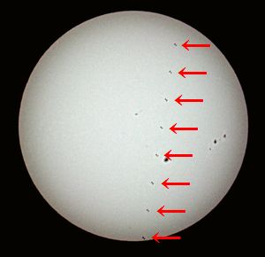 太陽の中心付近を横切る宇宙ステーション（矢印部分、８枚の写真を合成、堀さん提供）