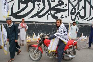 　１５日、アフガニスタン・カブールの交差点で、タリバン旗を買う若者ら（共同）