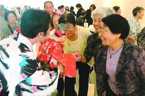 えびす人形と握手する高齢者=板野町犬伏の町文化の館