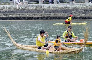 アシ舟で川を移動する参加者＝徳島市の新町川