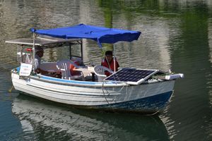 太陽光パネルを載せたソーラー船の試験航行をする新町川を守る会の池田さん（左）ら＝徳島市の新町川