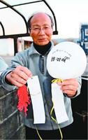 韓国から飛来したとみられる風船とメッセージカードを持つ大津さん=阿南市宝田町平岡