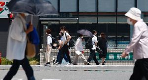 逃げ水が現れるほどの暑さの中、マスク姿で歩く人たち＝6月7日午後2時ごろ、徳島駅前