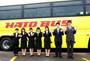 　入社式を終え、はとバスを背にポーズをとる新入社員＝１日午前、東京都大田区