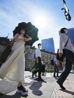 　強い日差しの中、日傘を差して歩く人たち＝２９日午前、ＪＲ東京駅前