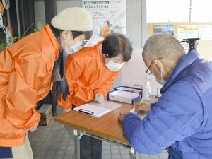 住民投票の実施に必要な署名をする市民(右)=徳島市新蔵町3の事務所