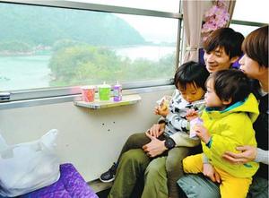 低速で走る列車で景色を楽しむ親子連れ=海陽町宍喰浦